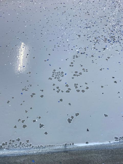 Customer review photograph showing scattered irregular marks in a grey flake garage coating